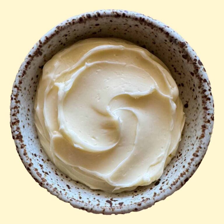 A photo of a bowl of homemade butter with a yellow background